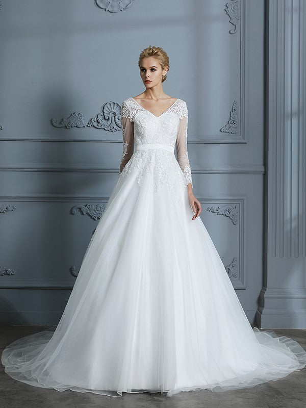 Vestido de novia de tul con escote en V y mangas largas y cola de corte.