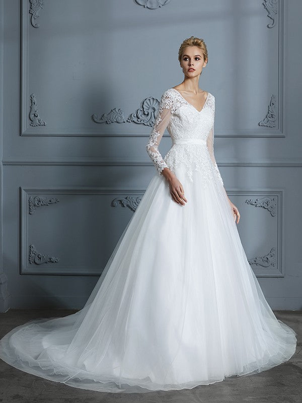 Vestido de novia de tul con escote en V y mangas largas y cola de corte.