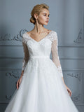 Vestido de novia de tul con escote en V y mangas largas y cola de corte.