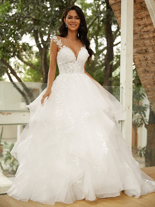 Vestido de novia de tul con apliques y escote en V, sin mangas y cola capilla.