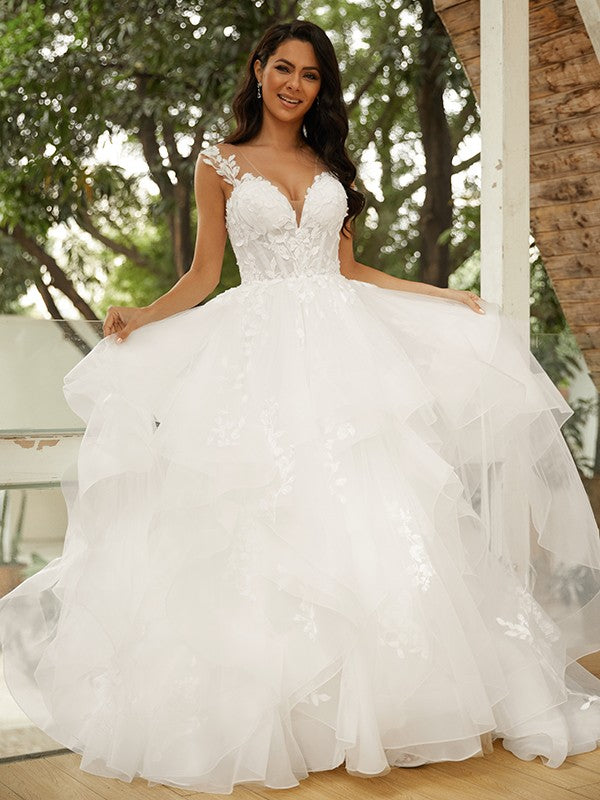 Vestido de novia de tul con apliques y escote en V, sin mangas y cola capilla.