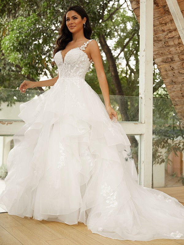 Vestido de novia de tul con apliques y escote en V, sin mangas y cola capilla.